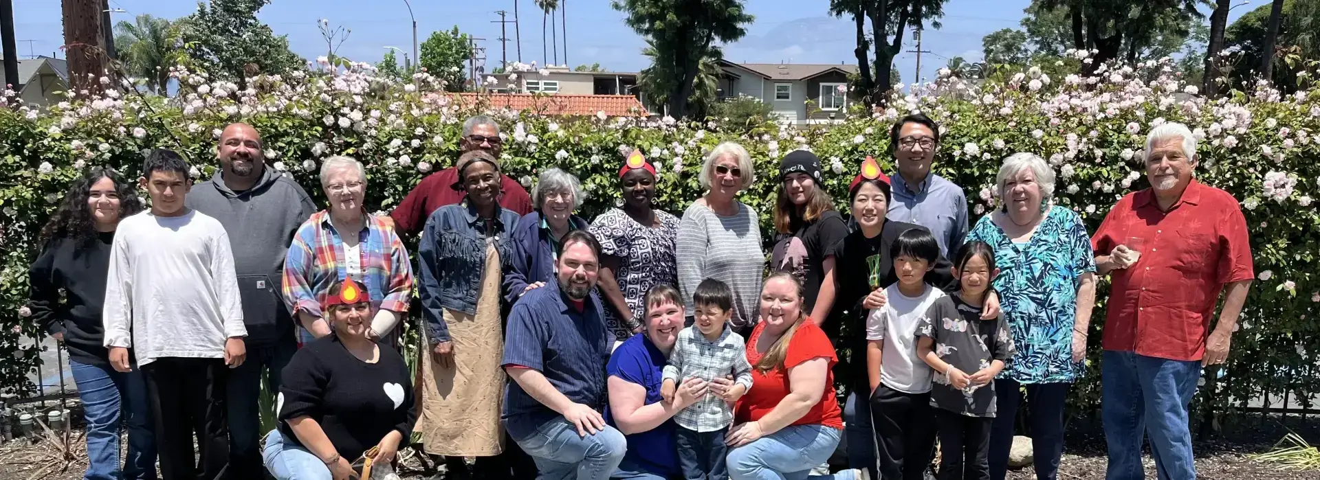 Multigenerational family enjoying a sunny garden gathering with smiles and colorful flowers.